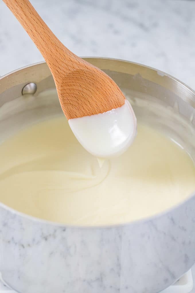 Remplissage de tarte à la crème de coco dans une casserole avec une cuillère en bois