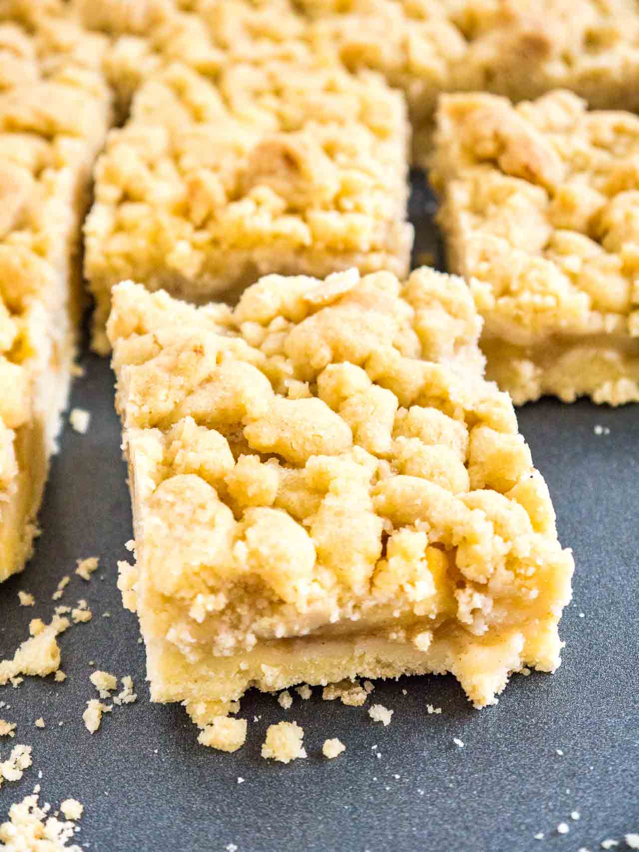 Des morceaux de gâteau aux pommes streusel sur une plaque de cuisson gris foncé.