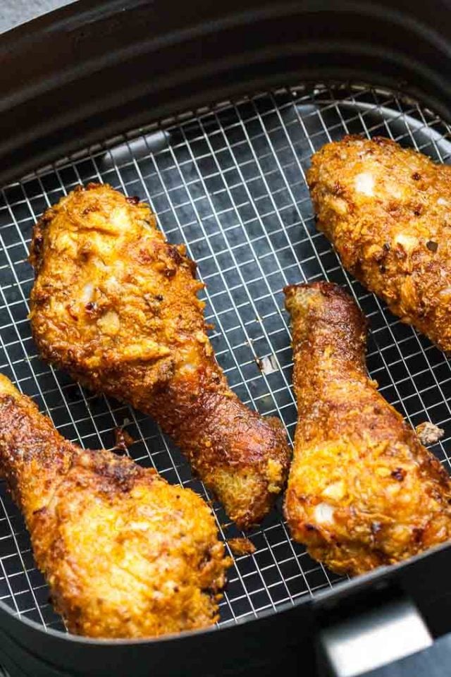 cuisses de poulet panées reposant dans un panier de friteuse à air