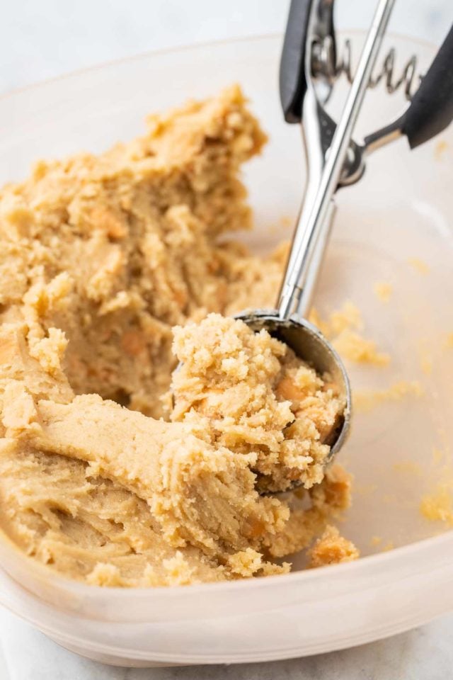 Pâte à biscuits au caramel beurre salé dans un bol en verre scoopée avec une cuillère à biscuits