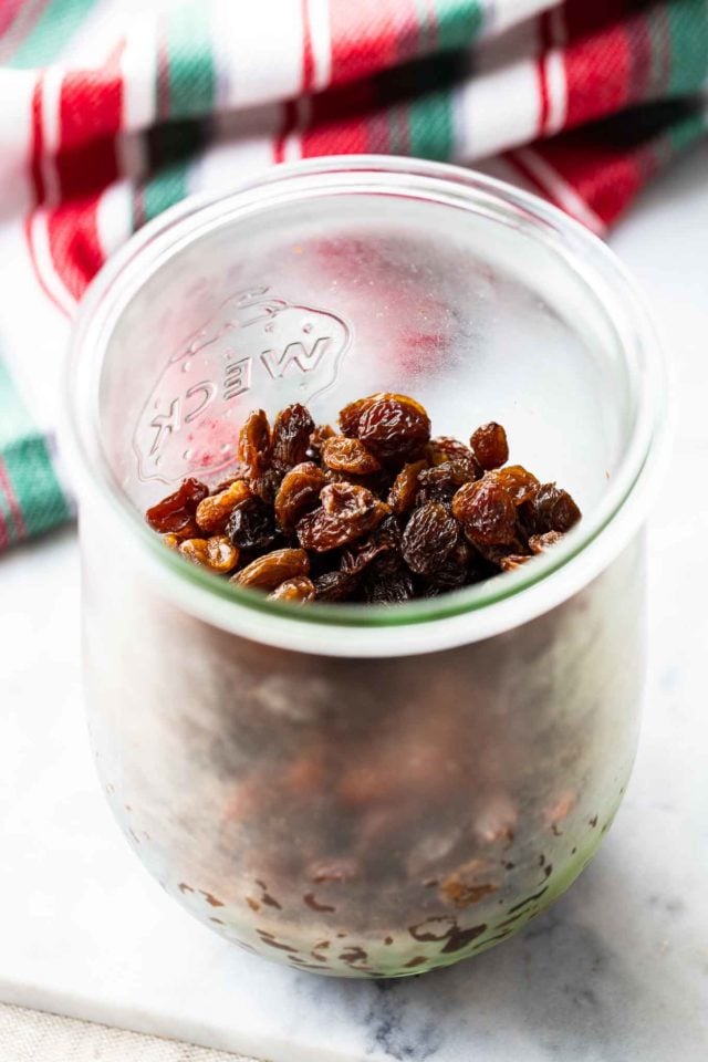 Un bocal Weck avec des raisins à côté d'un torchon rouge, blanc et vert.