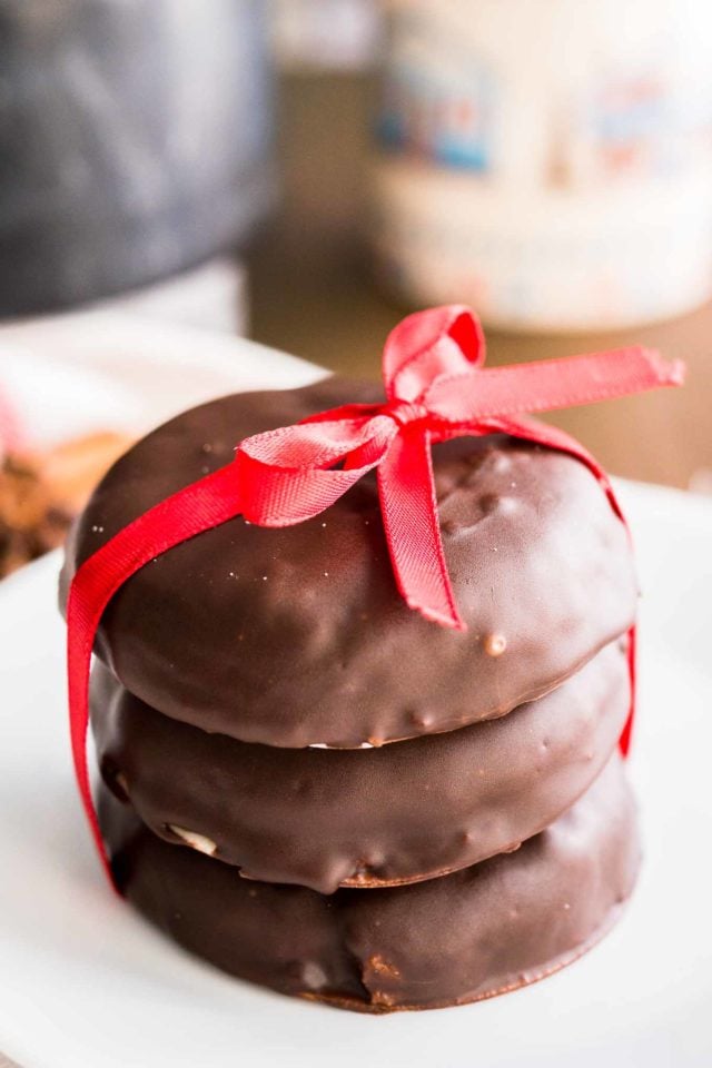 une pile de trois lebkuchen enrobés de chocolat avec un nœud rouge sur une assiette blanche