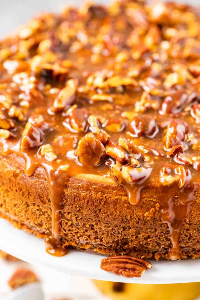 Un cheesecake entier garni de noix de pécan et de sauce caramel.