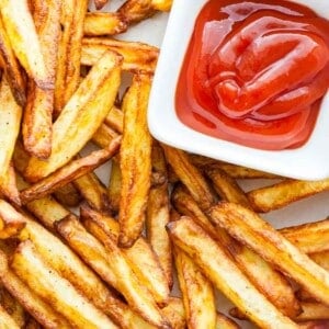 Vue de dessus de frites croustillantes avec un petit bol rectangulaire blanc de ketchup.
