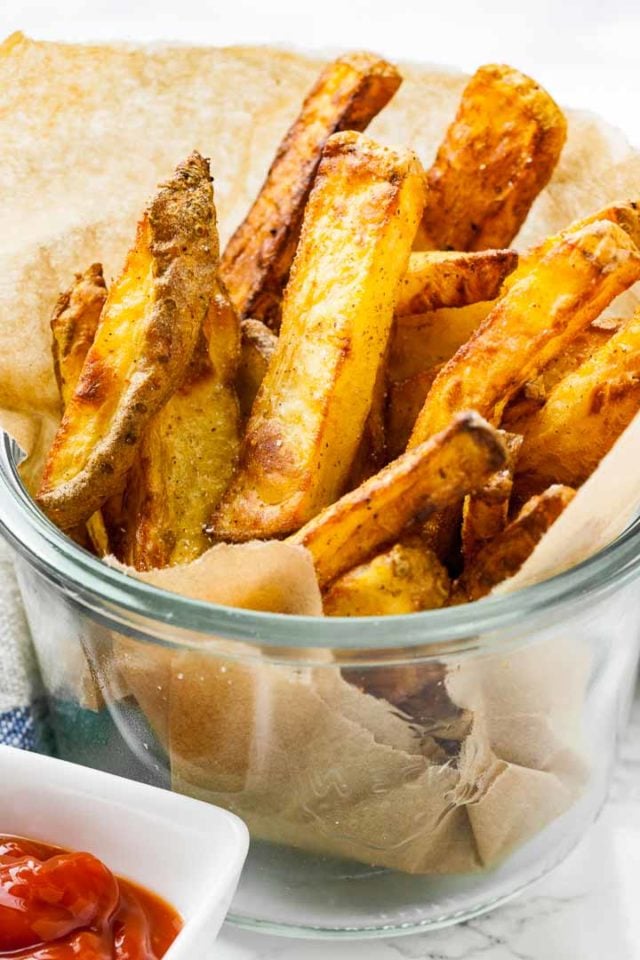 Un bocal Weck, rempli de papier sulfurisé, avec des frites croustillantes à l'intérieur.