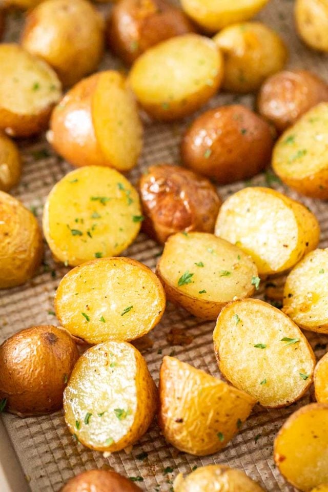 Gros plan d'une plaque de cuisson avec des pommes de terre rôties, garnies de persil.