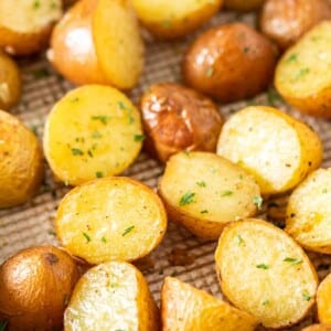 Gros plan d'une plaque de cuisson avec des pommes de terre rôties, garnies de persil.