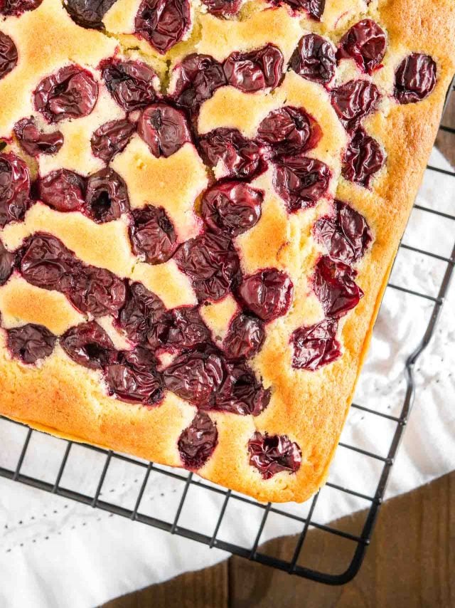 vue de haut d'un gâteau aux cerises sur une grille noire.