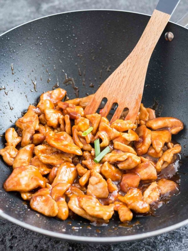 Un wok avec le poulet du Général Tso et une spatule en bois.