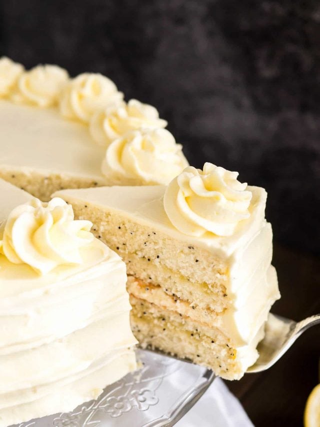 Gros plan d'un plat en verre avec un gâteau au citron et aux graines de pavot sur une table en bois avec une nappe blanche.