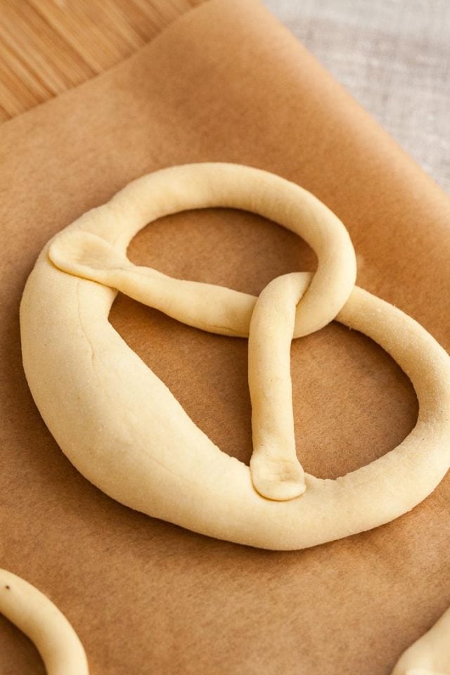 Pâte à bretzel, après avoir été tordue, est repliée, pour enfoncer les deux extrémités de la saucisse dans la partie épaisse de la pâte, créant la forme du bretzel.