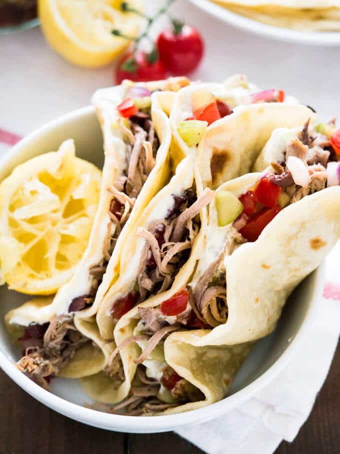 Délicieux tacos grecs avec tzatziki fait maison, gyros de porc effiloché à la mijoteuse et salsa grecque. Servis sur des tortillas de farine maison ! Une super variante des tacos classiques !