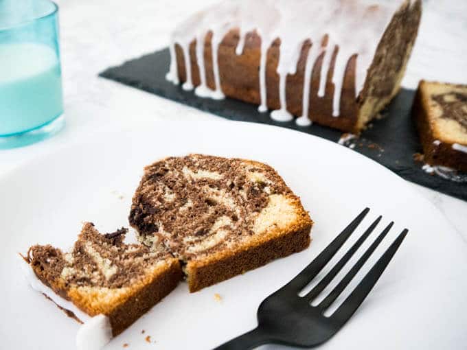 Le Gâteau Marbré à l'Orange est composé de deux pâtes parfumées à l'orange ! Ce délicieux gâteau a un glaçage au citron sur le dessus et se marie parfaitement avec une tasse de café.