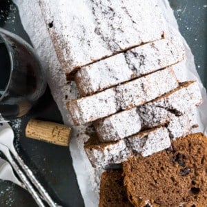 Vue du dessus d'un gâteau au vin rouge coupé en tranches. Un verre de vin rouge, un bouchon et quelques fourchettes à côté.