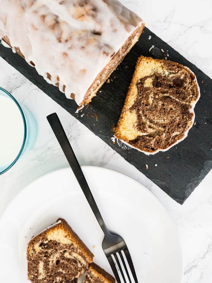 Le Gâteau Marbré à l'Orange est composé de deux pâtes parfumées à l'orange ! Ce délicieux gâteau a un glaçage au citron sur le dessus et se marie parfaitement avec une tasse de café.