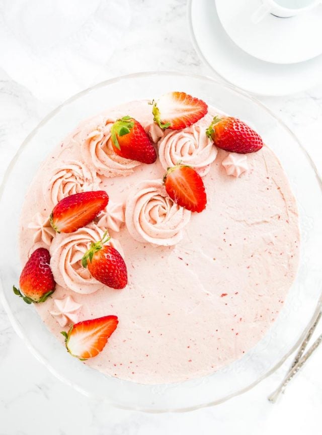 Vue de dessus d'un gâteau aux fraises sur un plat de service en verre.