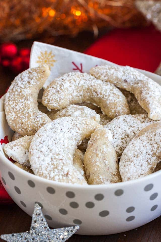 Un bol blanc avec des points argentés et une serviette, contenant des biscuits Vanillekipferl