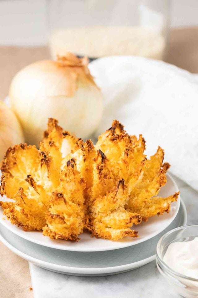 onion en fleurs sur une assiette blanche avec des oignons en arrière-plan