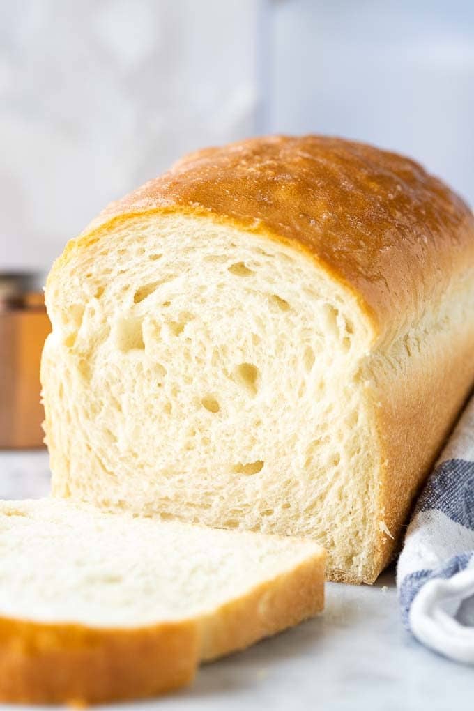 Pain blanc avec la première tranche coupée à côté d'un torchon blanc et bleu