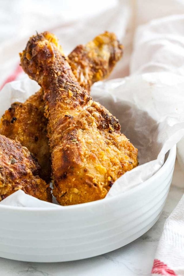 cuisses de poulet panées dans un bol blanc avec du papier sulfurisé