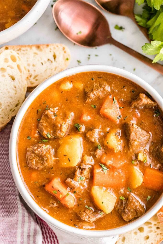 Un bol de ragoût de bœuf avec une cuillère et du pain à côté