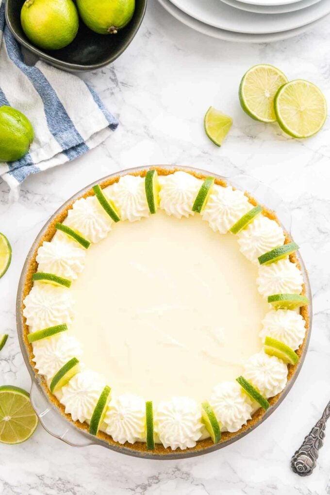 Une tarte au citron vert décorée de crème fouettée et de rondelles de citron vert