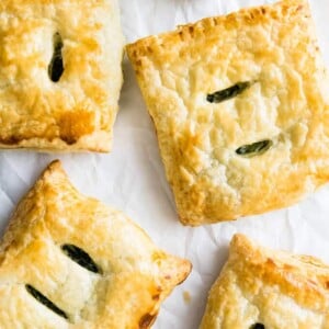 Vue de dessus des chaussons feuilletés aux épinards et ricotta sur du papier sulfurisé froissé.