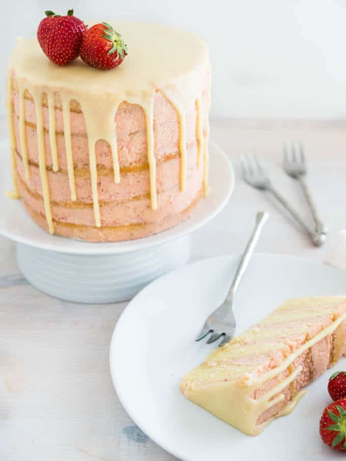 Le Naked Strawberry Layer Cake est réalisé avec une crème au beurre meringuée à la fraise fraîche et des couches de gâteau à la vanille aériennes. Terminé par un coulis de ganache chocolat blanc sur les bords, ce gâteau est une magnifique pièce maîtresse pour chaque occasion spéciale !